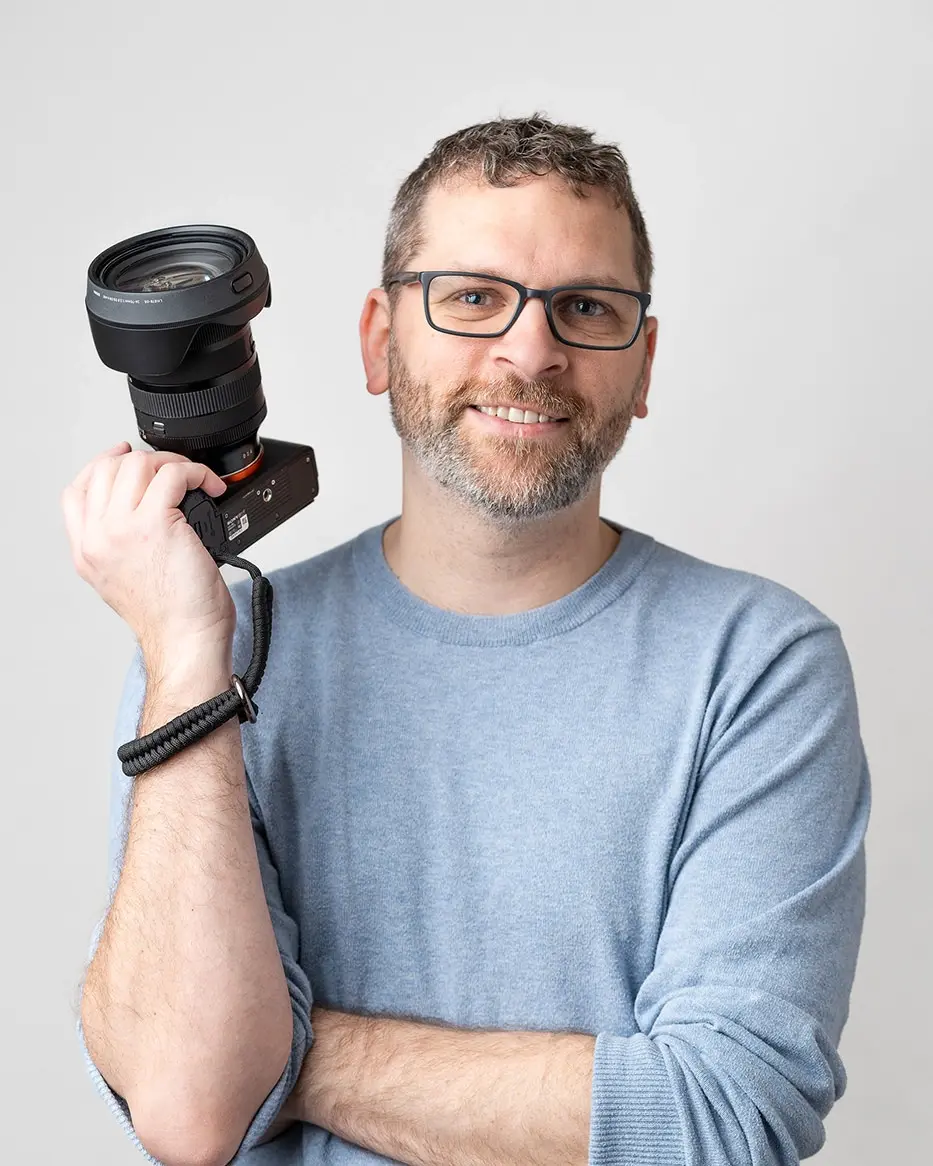 Jason of Jason Kyle Photography, holding his camera up with a smile